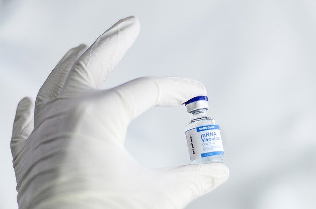 Gloved hand holding an mRNA vaccine bottle