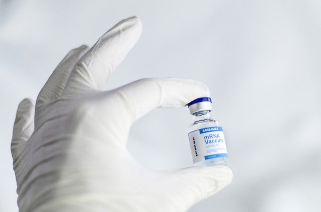 Gloved hand holding an mRNA vaccine bottle