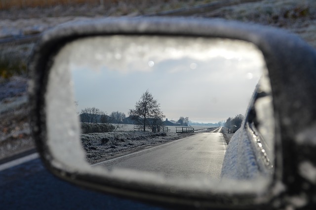 Car wing mirror view of winter road