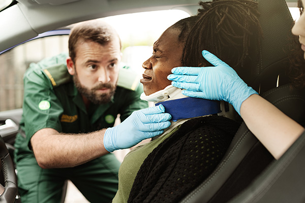 Paramedic helping a woman in a car with neckbrace for whiplash