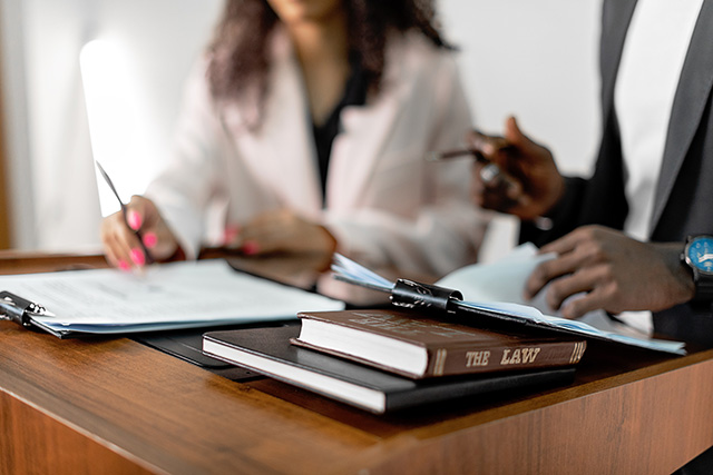 Solicitors with law books and legal papers - Photo by Mikhail Nilov on Pexels