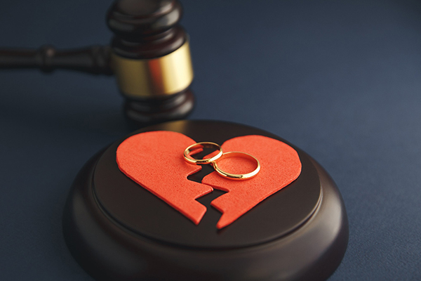 A red felt broken heart with 2 wedding rings and a gavel