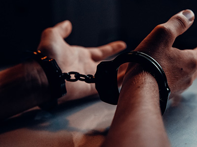 Hands on a table in handcuffs - Photo by Kindel Media on Pexels