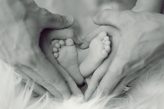 Heart shape made from parents hands around baby feet