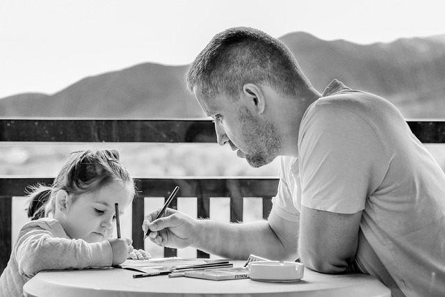 Parent helping child writing at a table - Image by Daniela Dimitrova from Pixabay