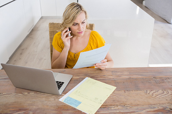 Business woman sitting at desk on the phone chasing unpaid invoices