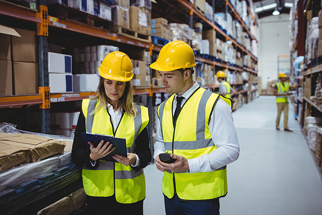 Two warehouse workers checking over paperwork